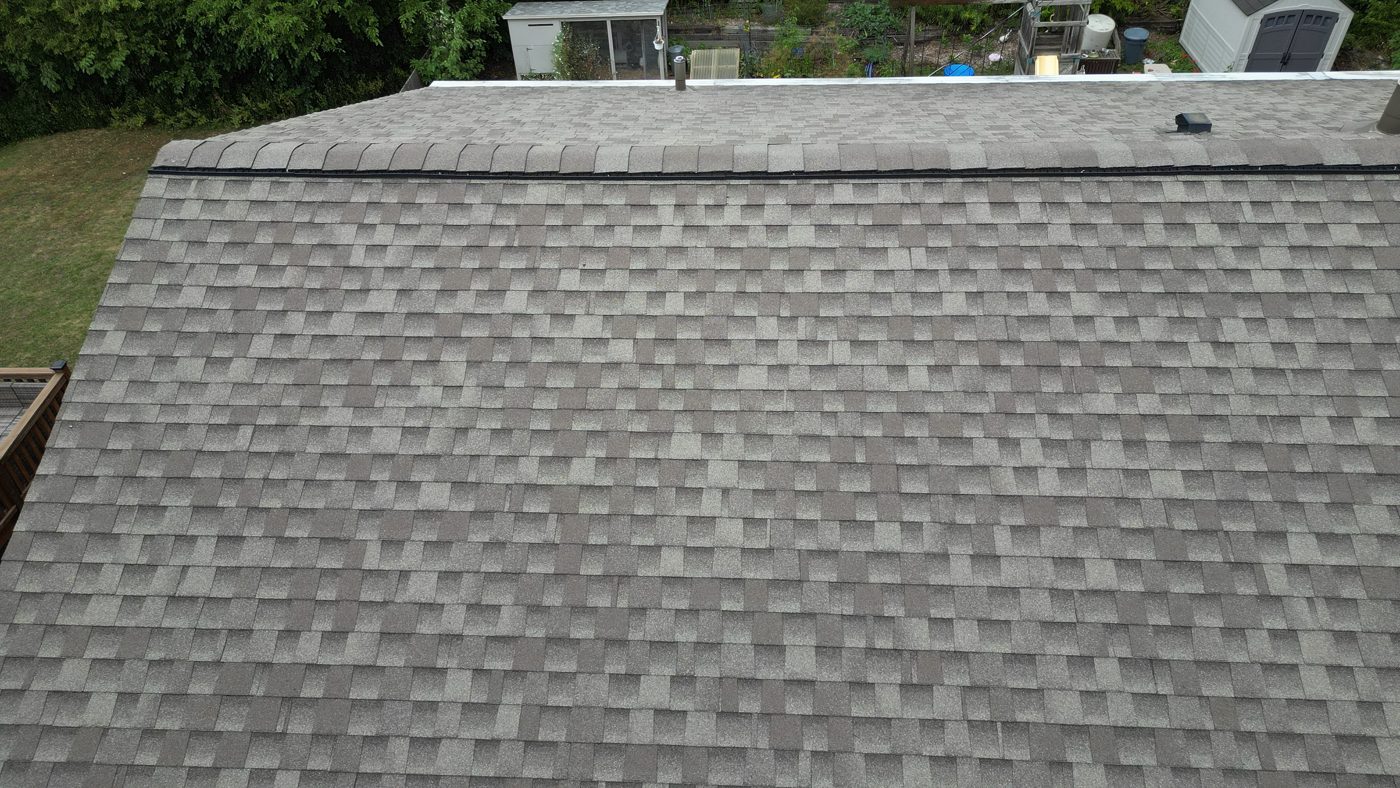 A newly installed architectural shingle roof with ridge vent, seen from a drone